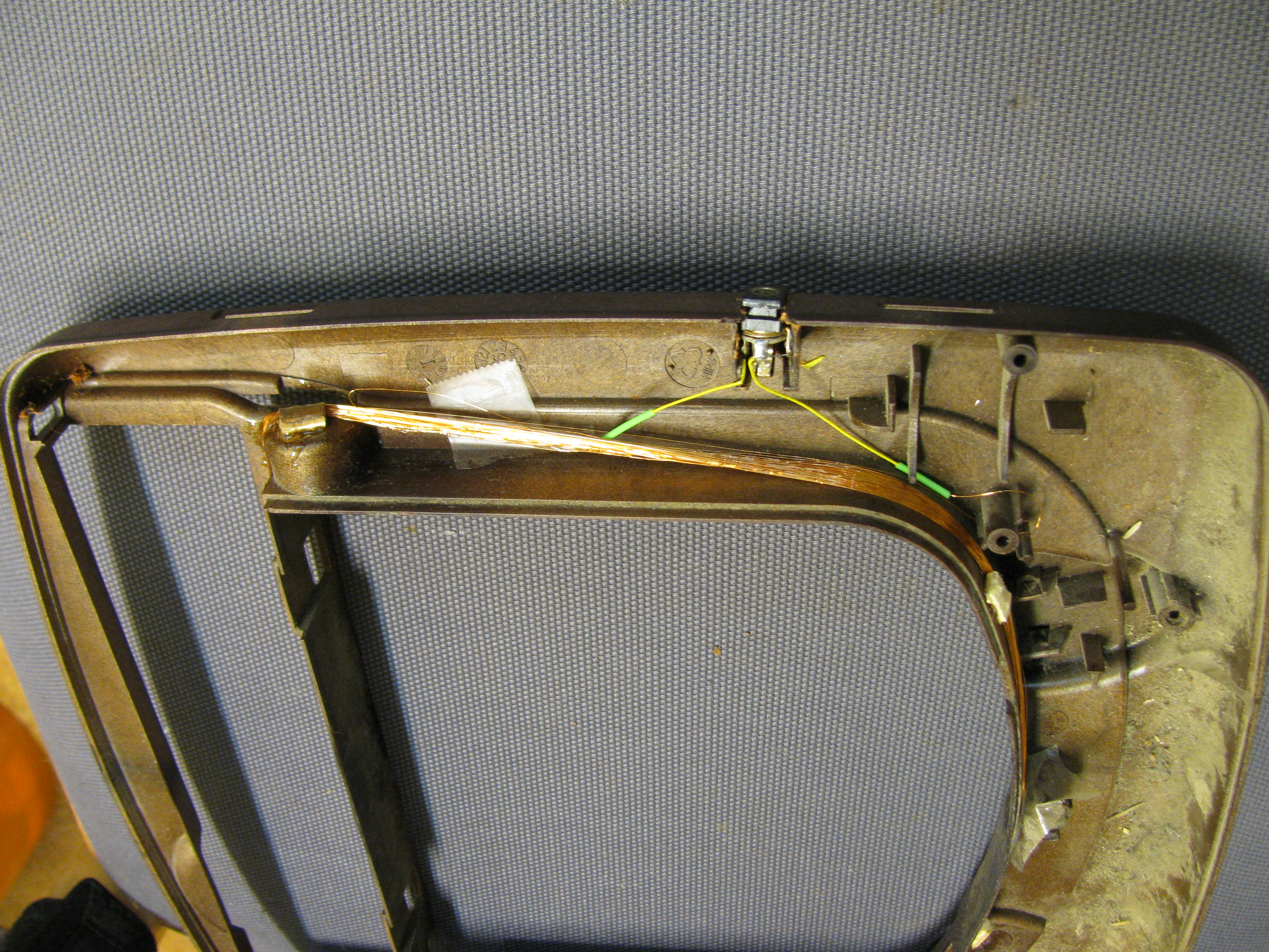 Copper colored coil of fine wire on the inside of a brown cat flap